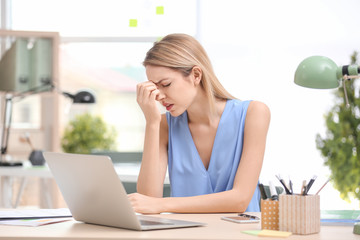 Wall Mural - Young woman suffering from headache in office