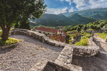 Stone Staircase, Chapel And Traditional Serbian Church With Bell Tower At Gradiste Monastery Near Buljarica, Montenegro. Mountains, Churchyard And Abbey Under Evening Lights .