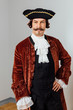 mustachioed eccentric man in the vintage clothes of the baron. Hat tricorn, brown jacket.