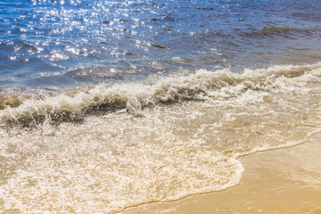 Coast of the sea on a sunny day with blue waves and yellow sand - the concept of relaxation