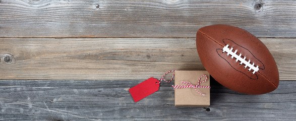 Fathers day gift box and single football on rustic wooden plank background