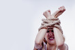 © zwiebackesser - Woman screaming from pain. Her hands are tied up with strong rope as symbol of the experience of grief, fear and inexpressible pain