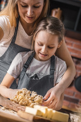 Sticker - Joyful happy mother and daughter standing on kitchen and preparing the dough on kitchen.