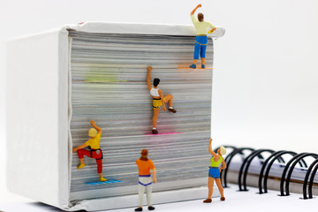 Wall Mural - Miniature people climbing book with challenging route on cliff, Concept of the path to purpose and success.