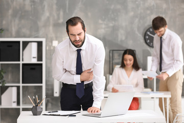 Canvas Print - Young man suffering from stomach ache in office