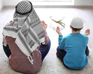 Wall Mural - Muslim father and son praying together, indoors