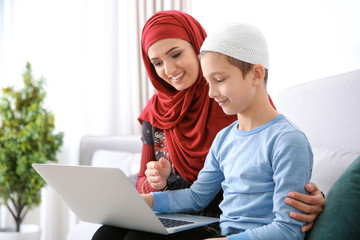 Wall Mural - Muslim woman using laptop with her son at home