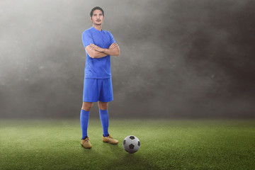 Wall Mural - Handsome asian football player with crossed arms