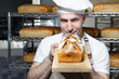 Chleb.
Przystojny piekarz z bochenkiem świeżego chleba stoi w piekarni.
