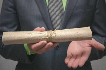 Businessman holds in hand a rolled up document scroll. Signing of an agreement. Conclusion of a business contract. Business deal concept. Special offer..