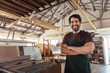 © mavoimages - Smiling woodworker standing in his workshop by a bench saw