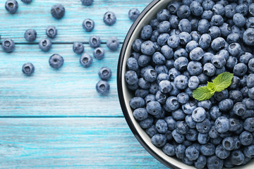 Canvas Print - Ripe blueberries in bowl on blue wooden table