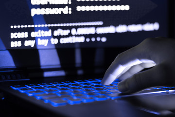 A computer programmer or hacker prints a code on a laptop keyboard to break into a secret organization system.