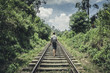 A male tourist walking along the railroad amidst the tropical forest of Sri-Lanka