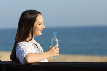 Wall Mural - Smiley woman holding a water bottle on the beach