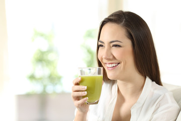 Wall Mural - Woman drinking a vegetable juice looking away