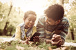 © Mladen - Young African American little girl and her father lying down in park and using mobile phone together.