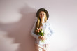© AnastazjaSoroka - A young beautiful girl with blond dissolved long hair, a felt hat on her head, keeps spring flowers in her hands on a sunny day. Women's Day.