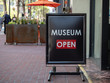 Museum open” sign sitting outside building