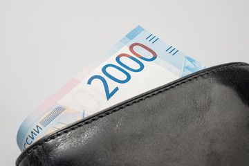 Wall Mural - Black natural leather wallet isolated on white background. Expensive man's purse closeup. New russian ruble banknote, Two thousand rubles.