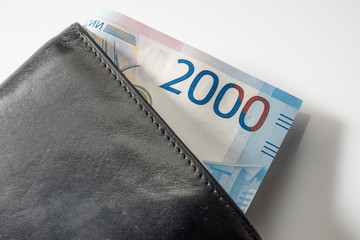 Black natural leather wallet isolated on white background. Expensive man's purse closeup. New russian ruble banknote, Two thousand rubles.