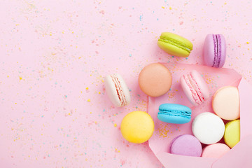 Creative composition with envelope and cake macaron or macaroon on pink pastel background top view. Flat lay.