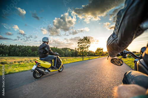 Motor biker riding on empty road with sunset light, concept of speed and touring in nature Fototapeta