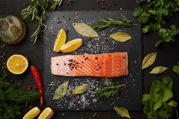 Wall Mural - Raw salmon with herbs and lemons on slate background