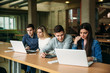 © Aleksandr - Group of college students studying in the school library, a girl and a boy are using a laptop and connecting to internet