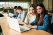 © Aleksandr - Group of college students studying in the school library, a girl and a boy are using a laptop and connecting to internet