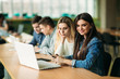 © Aleksandr - Group of college students studying in the school library, a girl and a boy are using a laptop and connecting to internet