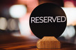 Close up of restaurant reserved table sign on table. Inscription denotes booked table in cafeteria. Don`t occupy this place! Table setting. Cafe desk for special occasion