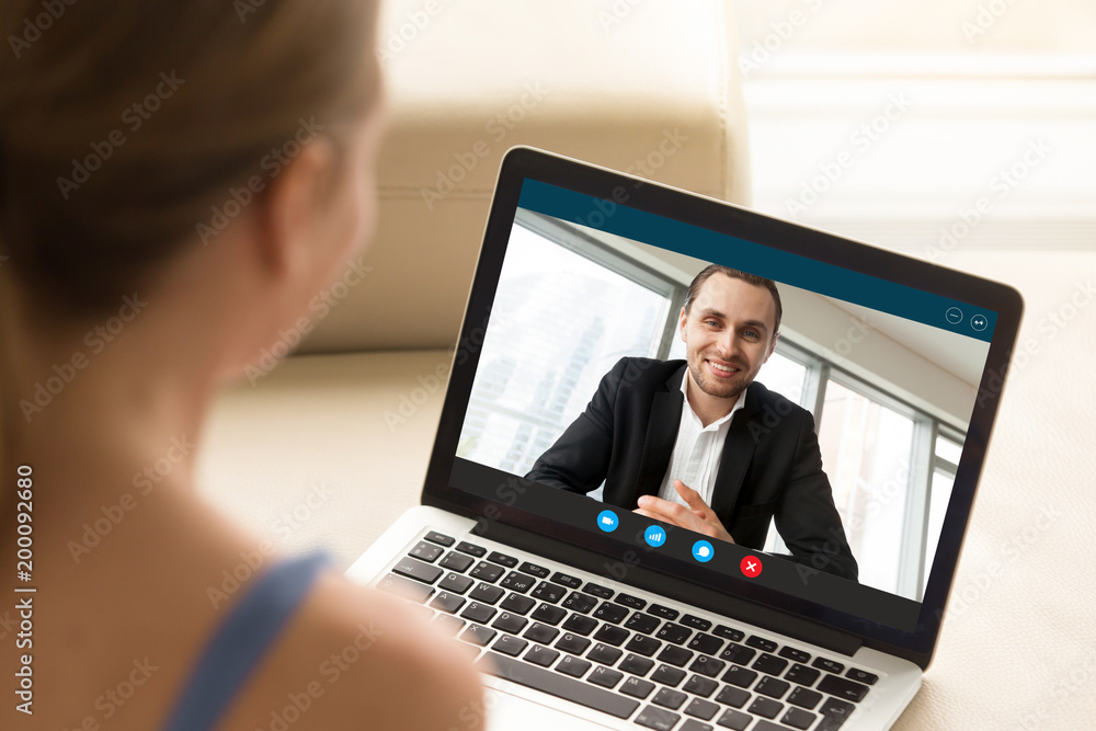 Young woman communicating with man in formal suit via video call application. Young couple chatting. Long distance relationship, virtual communication. Close up view over shoulder, focus on screen. - obrazy, fototapety, plakaty 