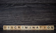 the word discrimination, consisting of light wooden square panels on a dark wooden background