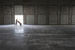 © Mint Images - Man walking with loaded hand truck past loading dock doors in new empty warehouse.