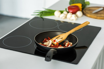 Wall Mural - frying pan with appetizing vegetables on electric stove in kitchen