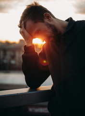 Thoughtful young man on background of cityscape at sunset.