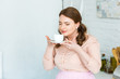 © LIGHTFIELD STUDIOS - beautiful woman sniffing coffee with closed eyes in kitchen