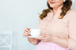 © LIGHTFIELD STUDIOS - cropped image of woman holding cup of coffee at kitchen