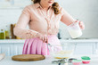 © LIGHTFIELD STUDIOS - cropped image of woman adding milk to dough at kitchen