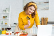 © LIGHTFIELD STUDIOS - smiling beautiful woman holding credit card and looking at laptop at kitchen