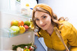 © LIGHTFIELD STUDIOS - beautiful woman opening fridge and holding wooden spatula at kitchen