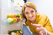 © LIGHTFIELD STUDIOS - beautiful smiling woman reaching hand in fridge at kitchen