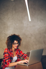 Wall Mural - Young woman sitting at cafe working on laptop