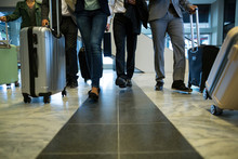 Businesspeople Walking With Luggage In Waiting Area