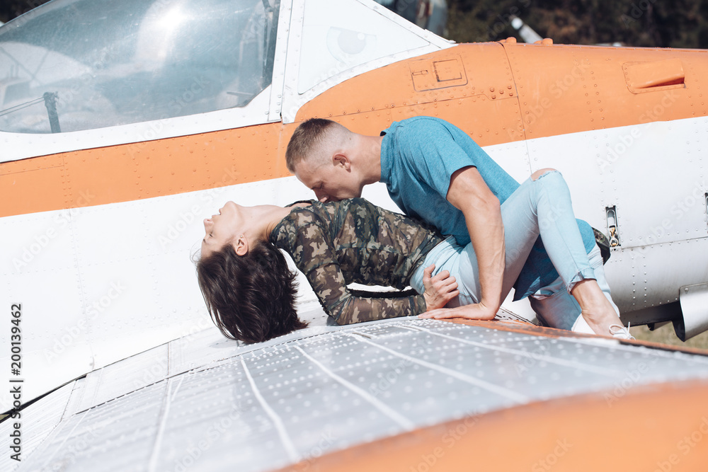 Photo Stock Couple makes love on wing of old plane on sunny day  