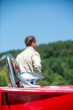 Unidentifiable man in race suit behind his race car and helmet, waiting for the start. Selective focus on the helmet in the foreground.