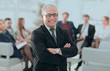 © ASDF - smiling senior boss in the background of the office