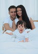 © ASDF - Portrait of a joyful family sitting on the bed at home