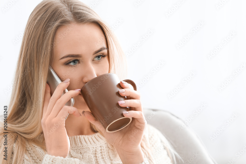 Beautiful woman talking on mobile phone against light background